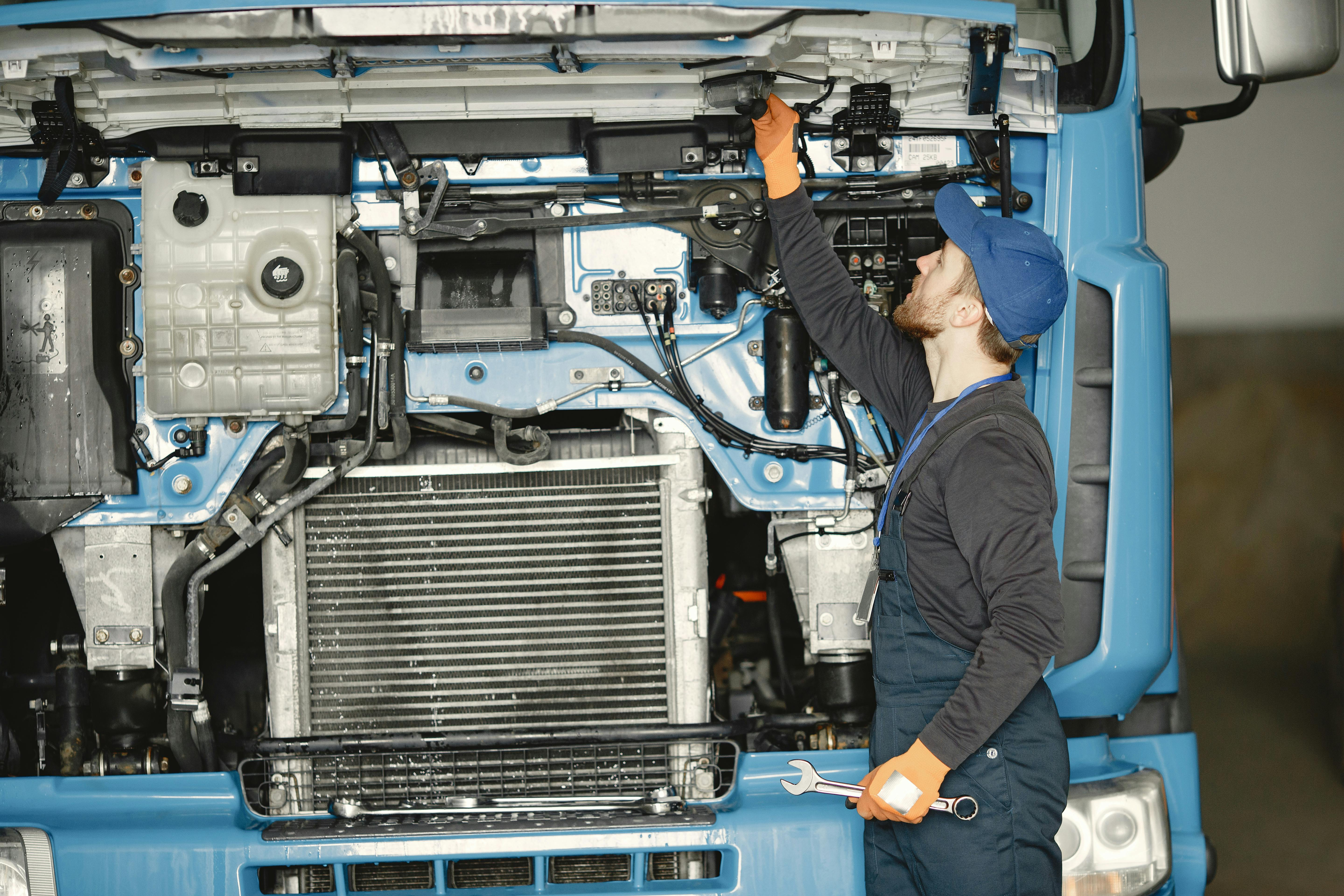 Professional diesel mechanic inspecting heavy-duty rig in shop bay